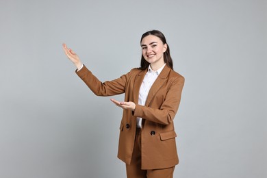 Photo of Happy businesswoman welcoming clients or partners on grey background