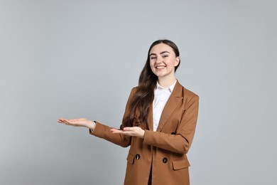 Photo of Happy businesswoman welcoming clients or partners on grey background