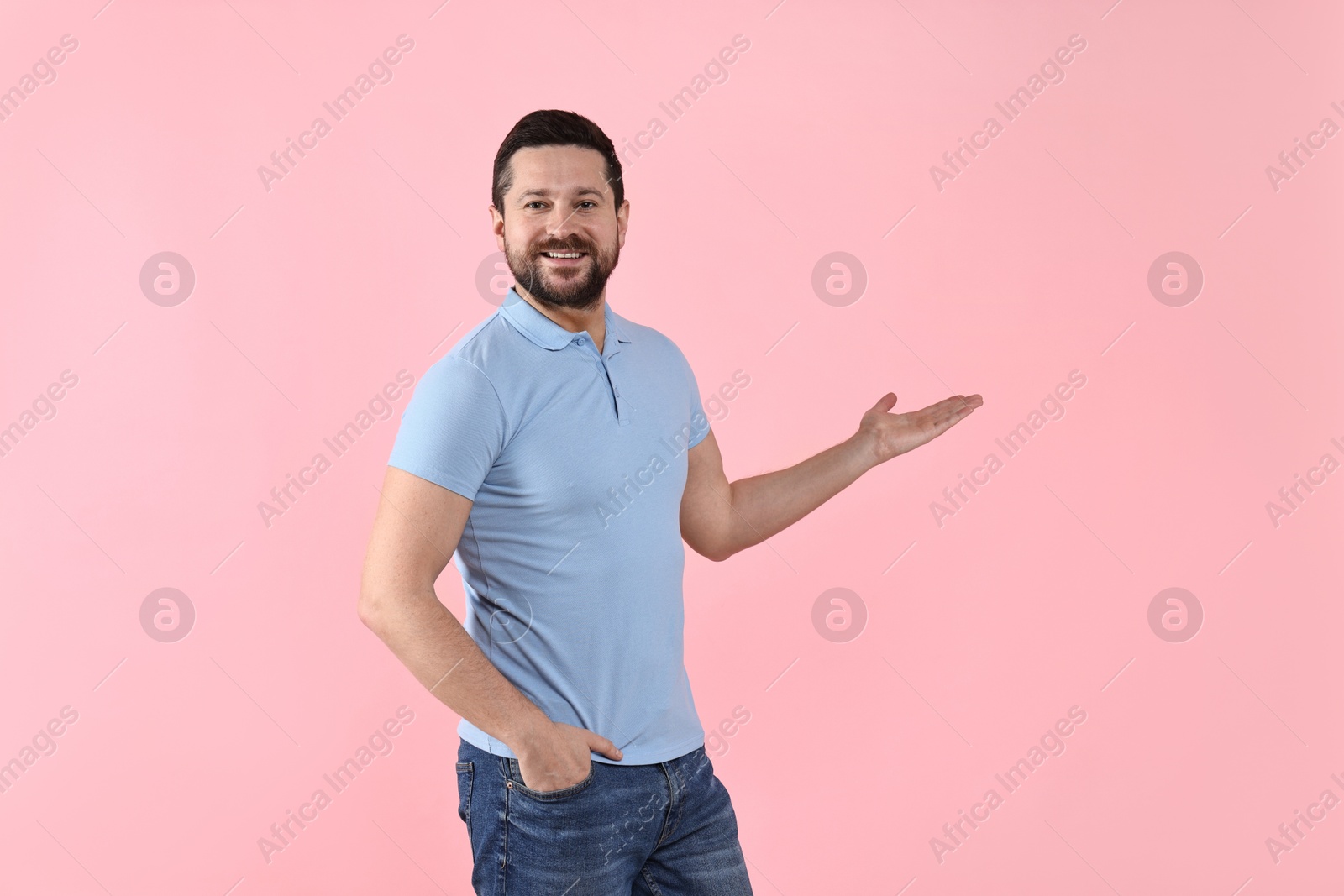 Photo of Happy man welcoming friends or guests on pink background