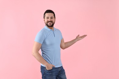 Happy man welcoming friends or guests on pink background