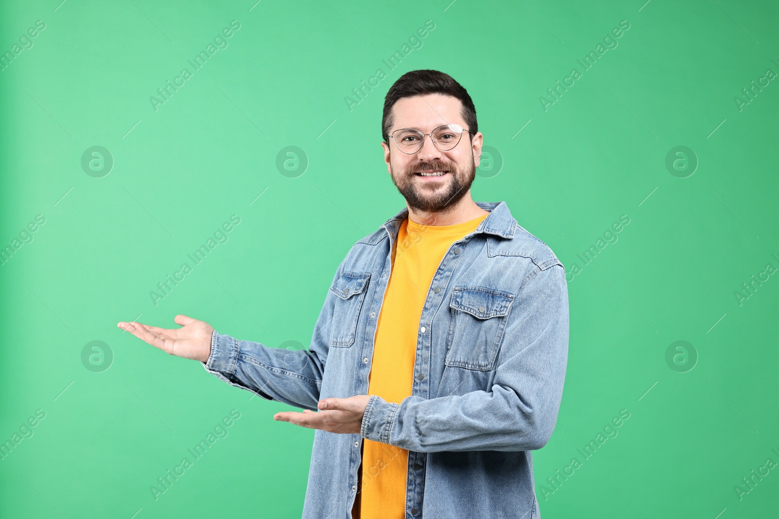 Photo of Happy man welcoming friends or guests on green background