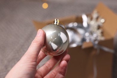 Photo of Woman holding Christmas bauble on blurred background, closeup