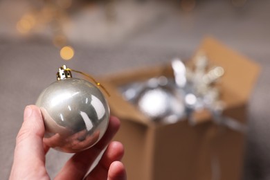 Photo of Woman holding Christmas bauble on blurred background, closeup. Space for text