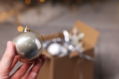 Photo of Woman holding Christmas bauble on blurred background, closeup. Space for text