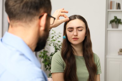 Photo of Psychologist using pendulum while working with patient during hypnosis session indoors