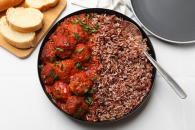 Photo of Tasty meatballs with sauce and brown rice on white tiled table, flat lay