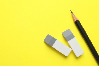 Photo of Erasers and pencil on yellow background, top view. Space for text