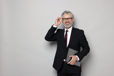 Photo of Portrait of banker with laptop on grey background, space for text