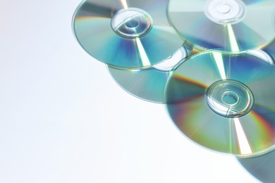 Photo of Many shiny compact discs on light background, closeup. Space for text