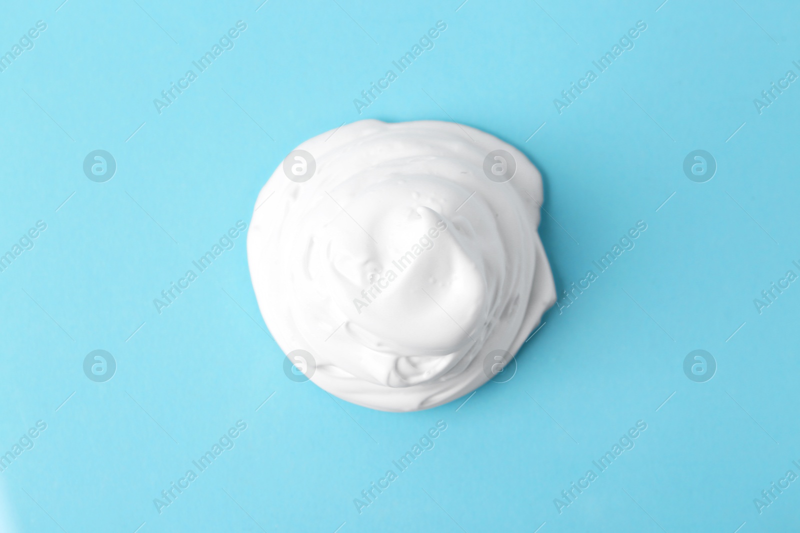 Photo of Sample of fluffy foam on light blue background, top view