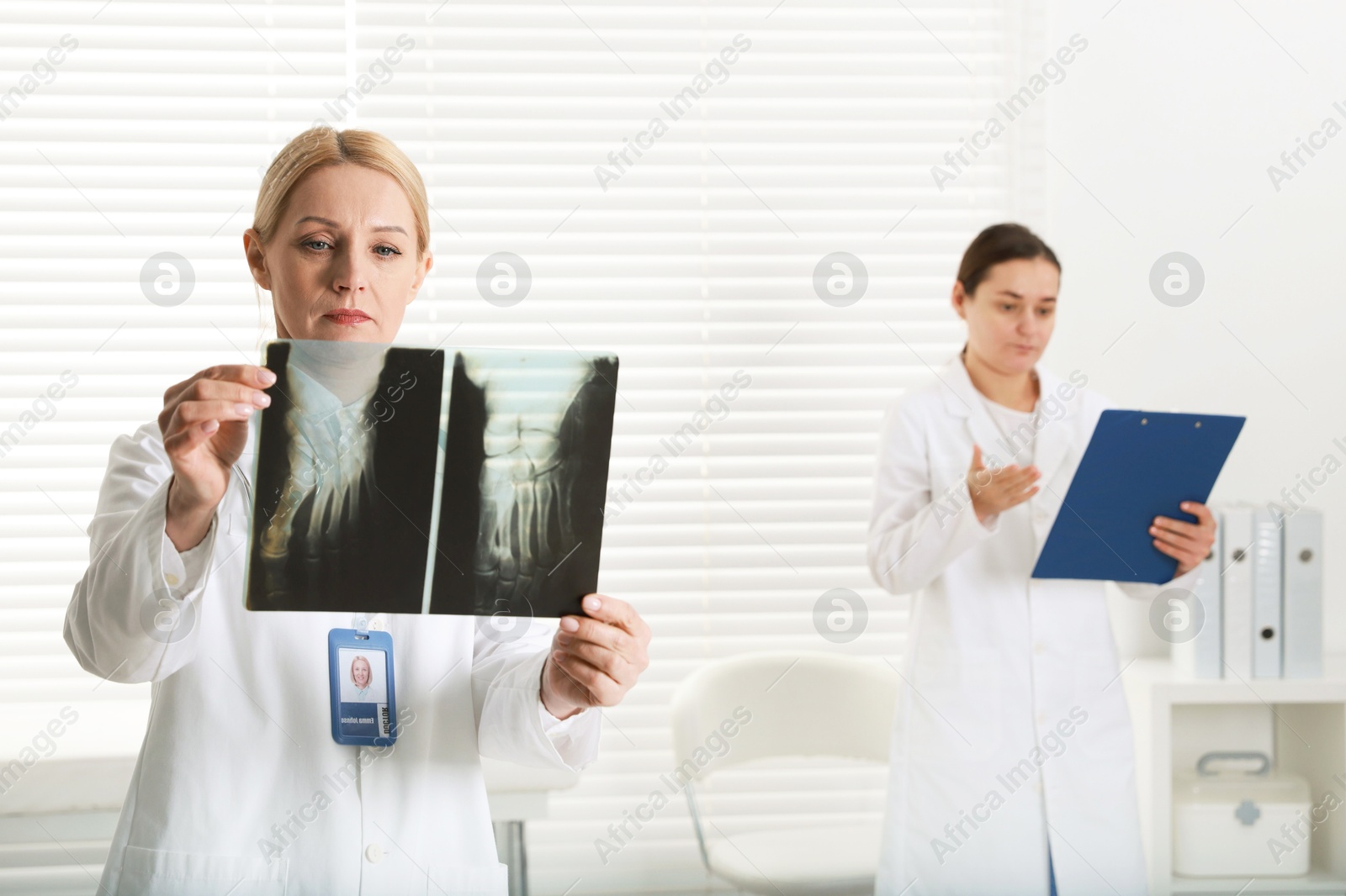 Photo of Doctor examining x-ray image of foot in clinic. Medical assistant with clipboard indoors