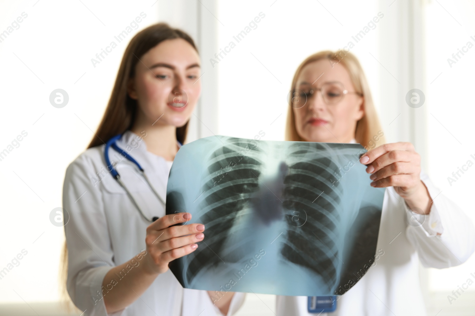 Photo of Doctors examining chest x-ray near window in clinic, selective focus