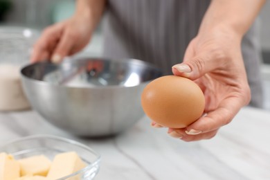 Photo of Making dough. Woman with fresh egg at white marble table, closeup