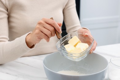 Photo of Making dough. Woman adding butter into bowl at white marble table, closeup