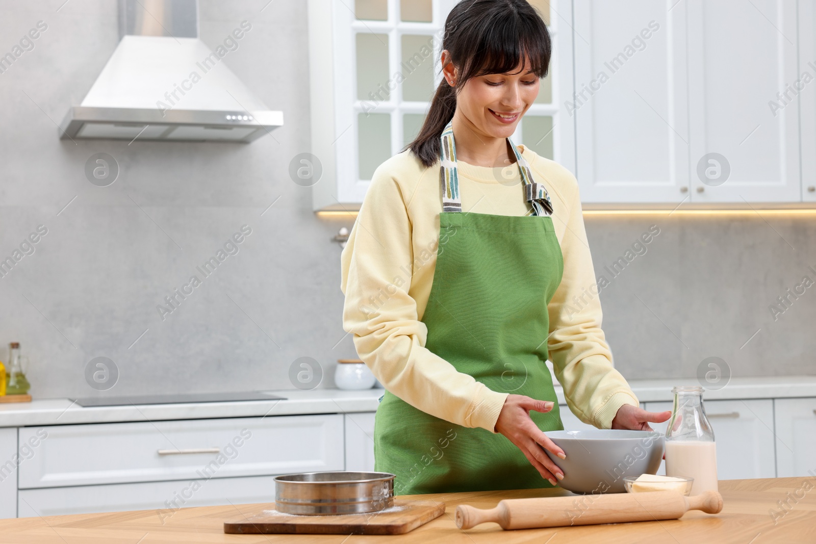 Photo of Woman making dough at wooden table indoors. Space for text