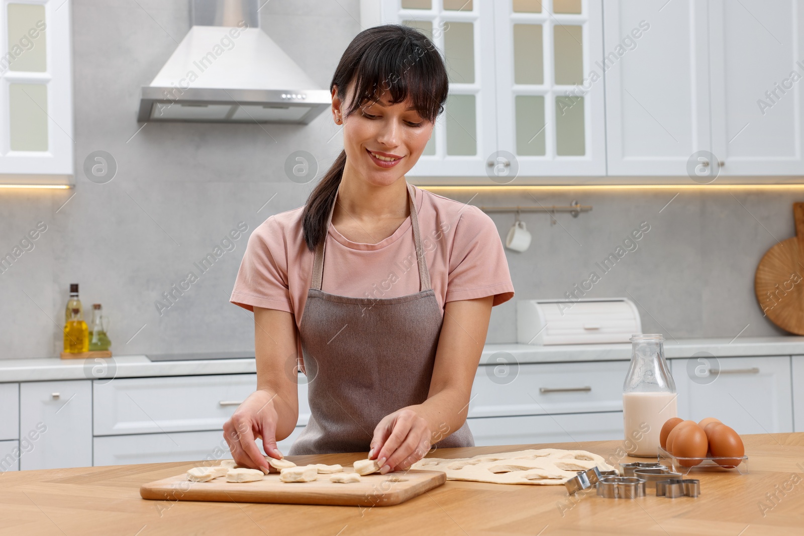 Photo of Woman with raw cookies at wooden table