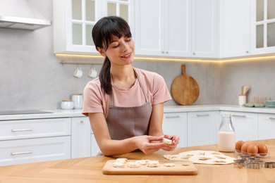 Photo of Woman with raw cookies at wooden table