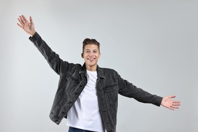 Photo of Happy man welcoming friends or guests on grey background