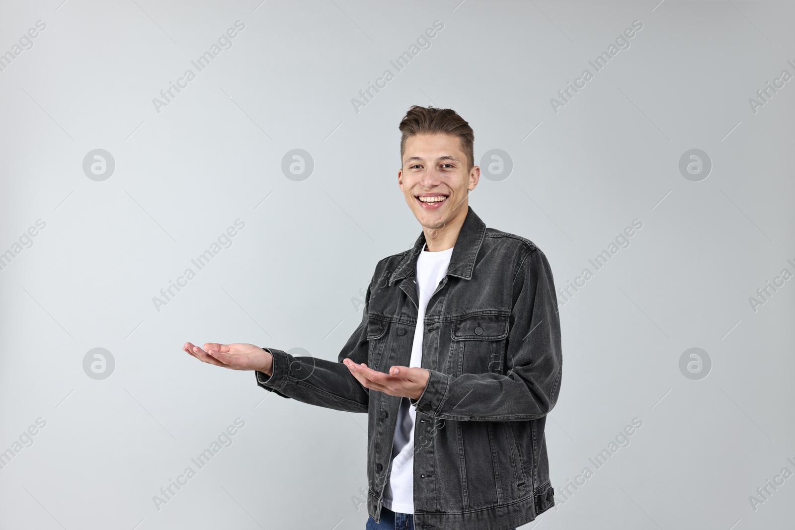 Photo of Happy man welcoming friends or guests on grey background