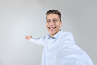 Photo of Happy businessman taking selfie and welcoming clients or partners on grey background. Space for text