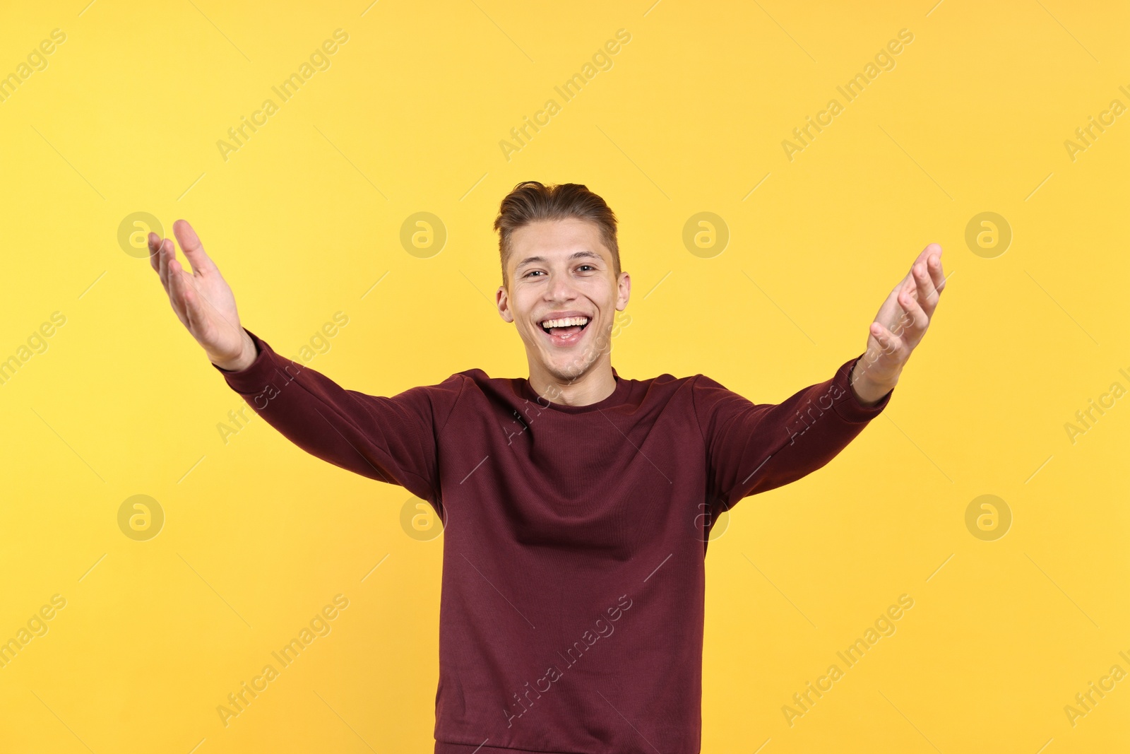 Photo of Happy man welcoming friends or guests on yellow background