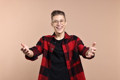 Photo of Happy man welcoming friends or guests on beige background