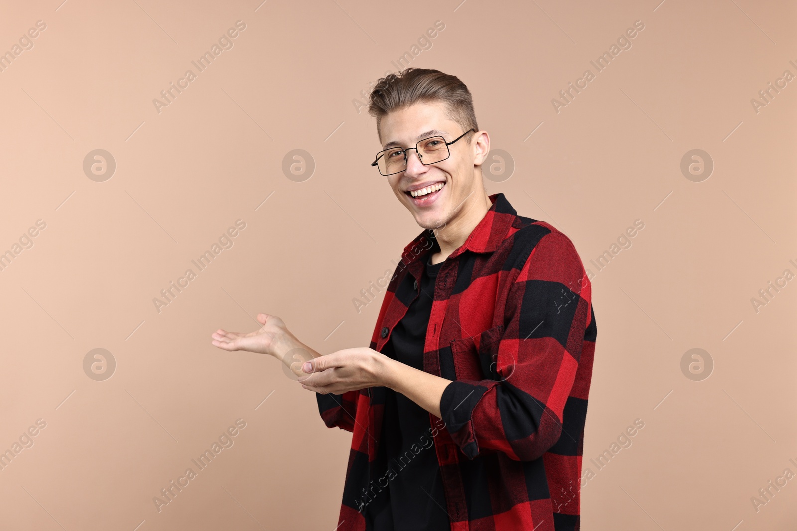 Photo of Happy man welcoming friends or guests on beige background. Space for text