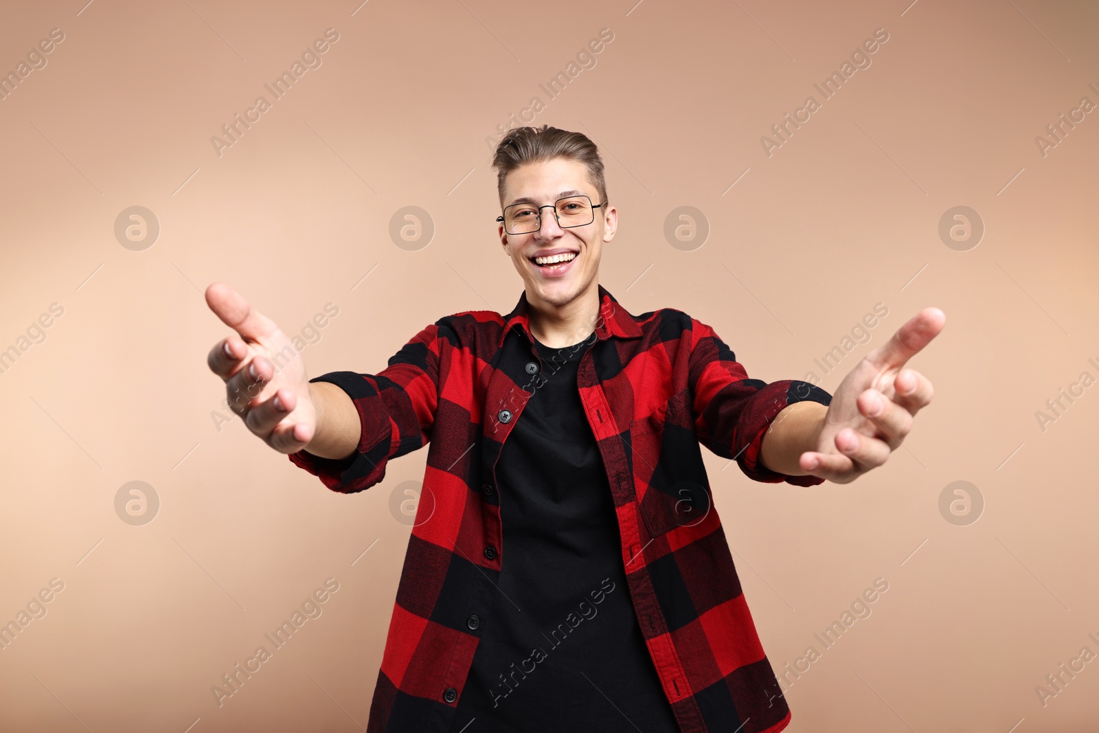 Photo of Happy man welcoming friends or guests on beige background