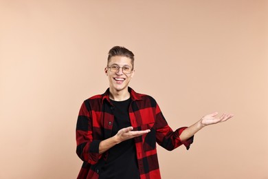 Photo of Happy man welcoming friends or guests on beige background