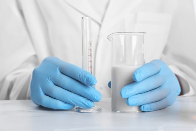 Photo of Laboratory testing. Scientist working with glassware at white marble table, closeup