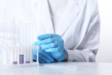 Photo of Laboratory testing. Scientist working with test tubes at white marble table, closeup