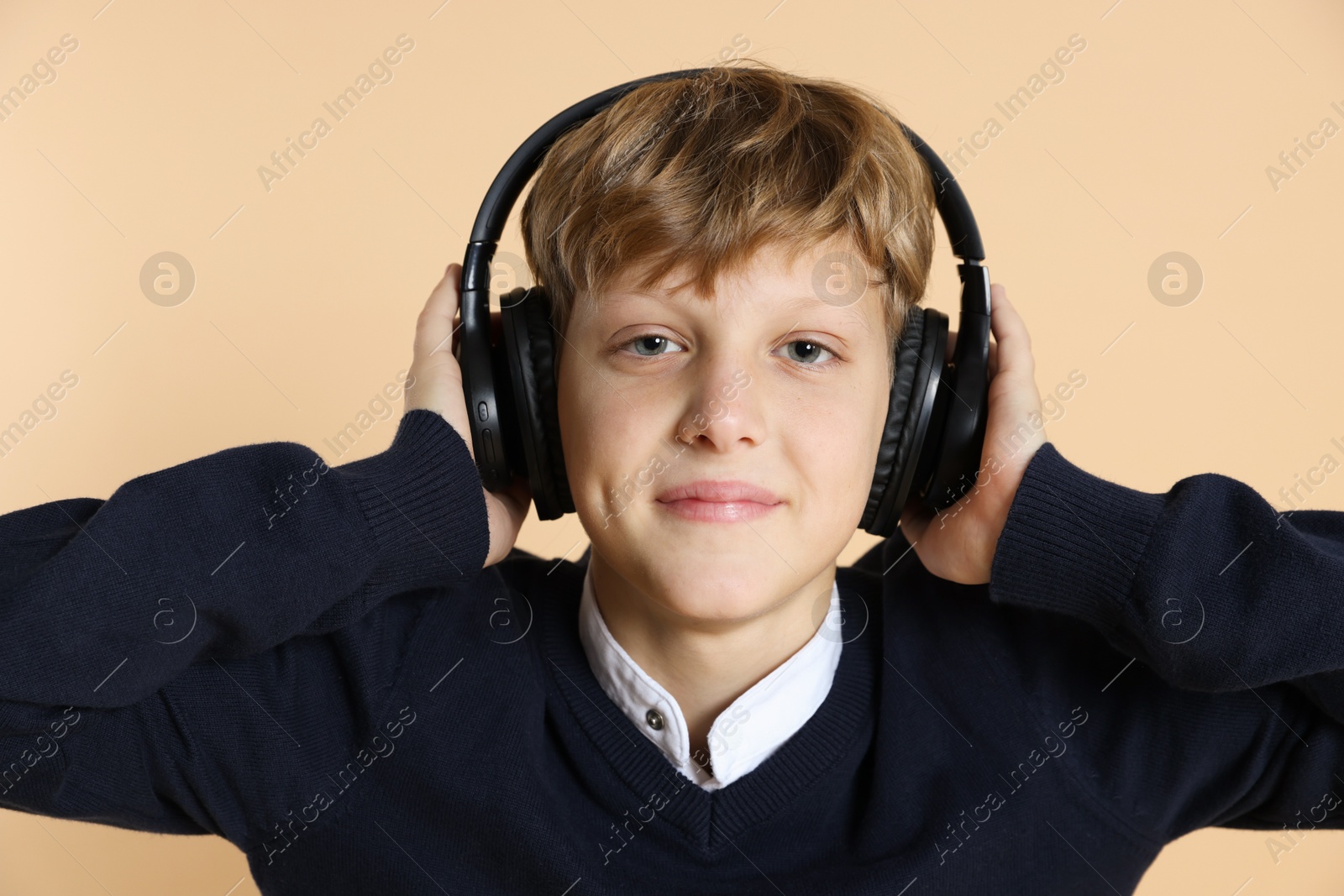 Photo of Portrait of teenage boy in headphones on beige background