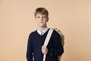 Photo of Portrait of teenage boy with backpack on beige background