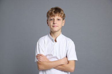 Photo of Portrait of teenage boy with crossed arms on grey background