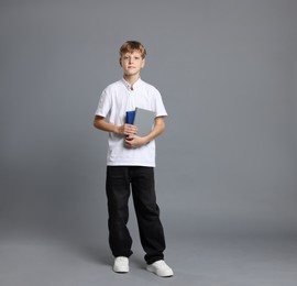 Photo of Full length portrait of teenage boy with books on grey background