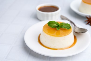 Photo of Tasty pudding with caramel sauce served on white tiled table, closeup. Space for text