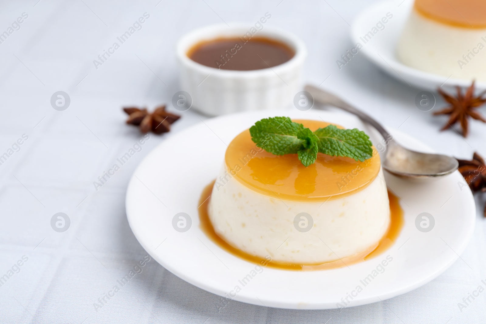 Photo of Tasty pudding with caramel sauce served on white tiled table, closeup. Space for text