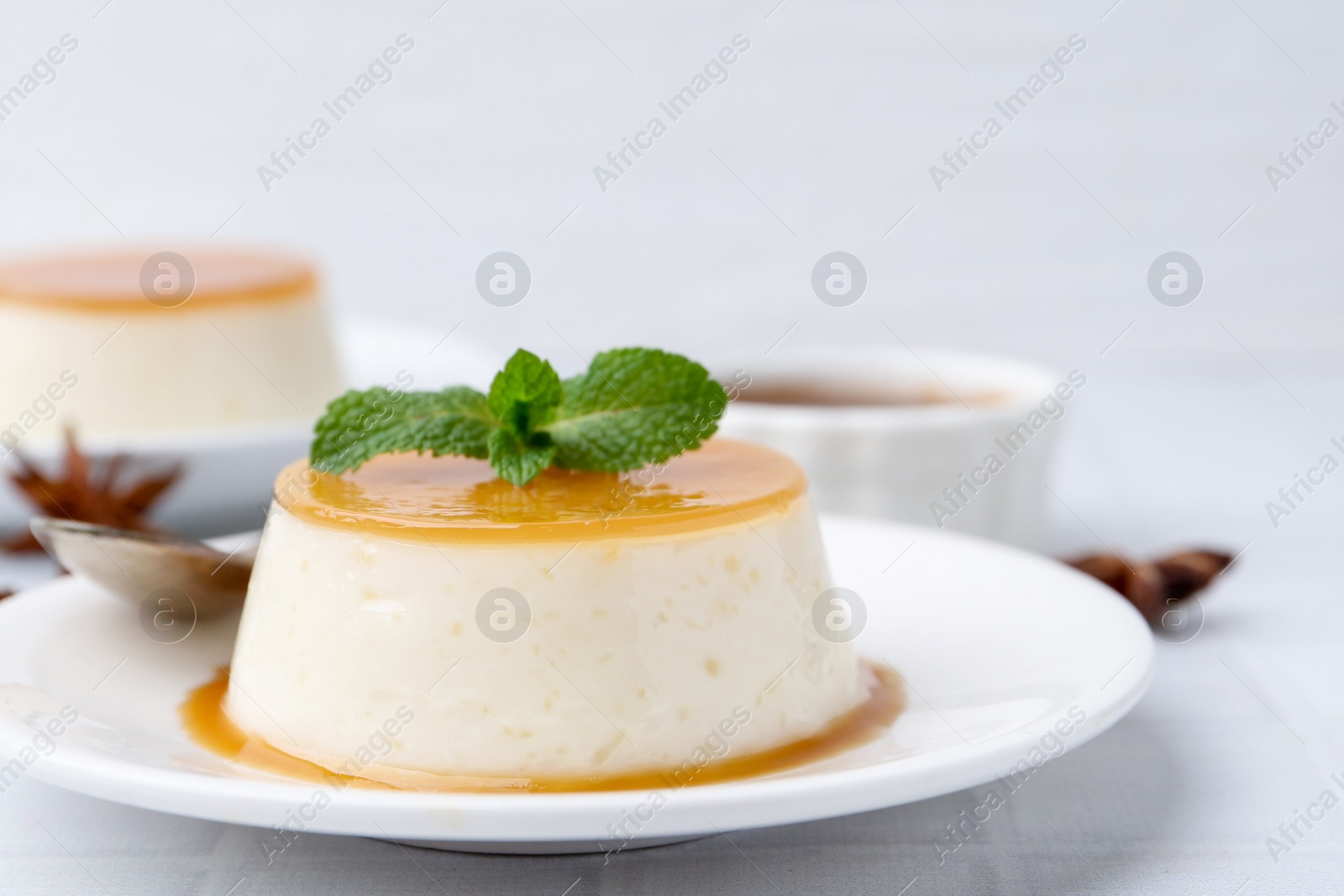 Photo of Tasty pudding with caramel sauce served on white tiled table, closeup