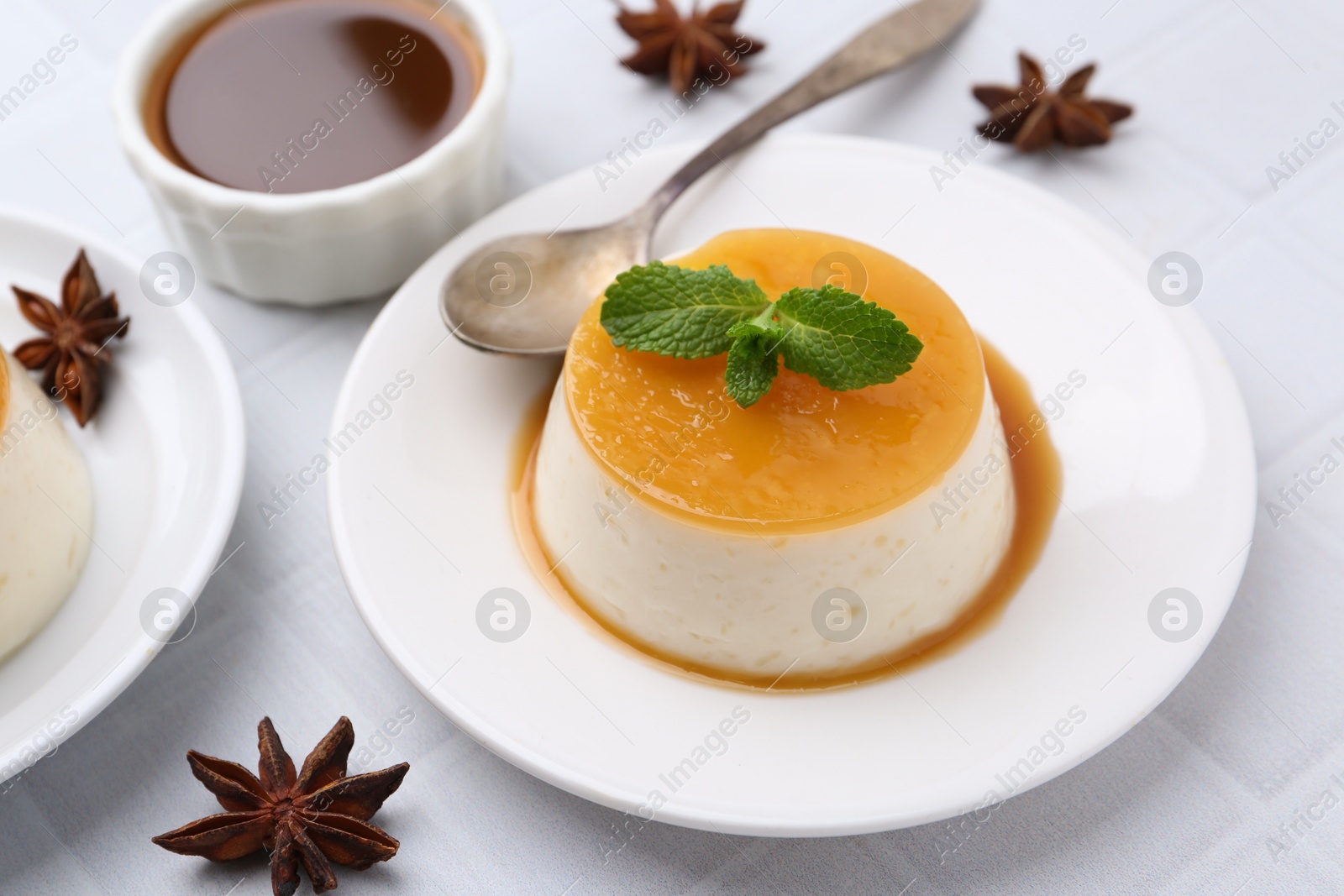 Photo of Tasty pudding with caramel sauce served on white tiled table, closeup