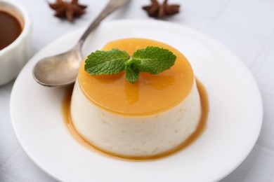 Photo of Tasty pudding with caramel sauce served on white tiled table, closeup