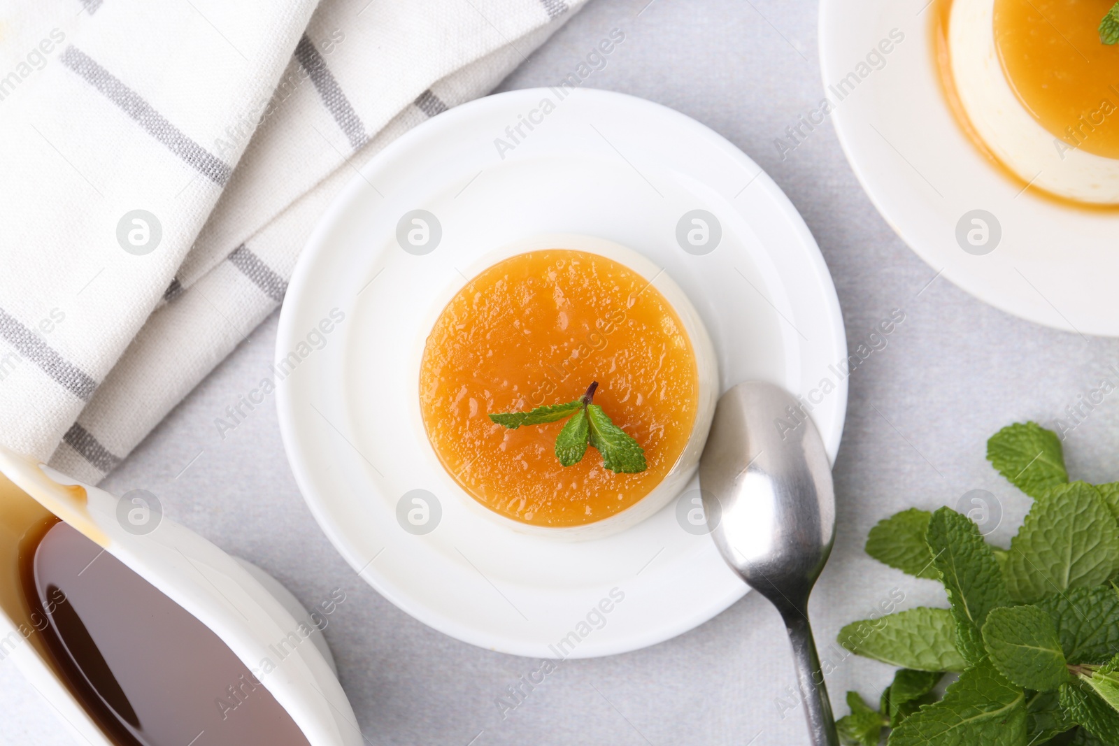 Photo of Tasty pudding with caramel sauce served on white table, flat lay