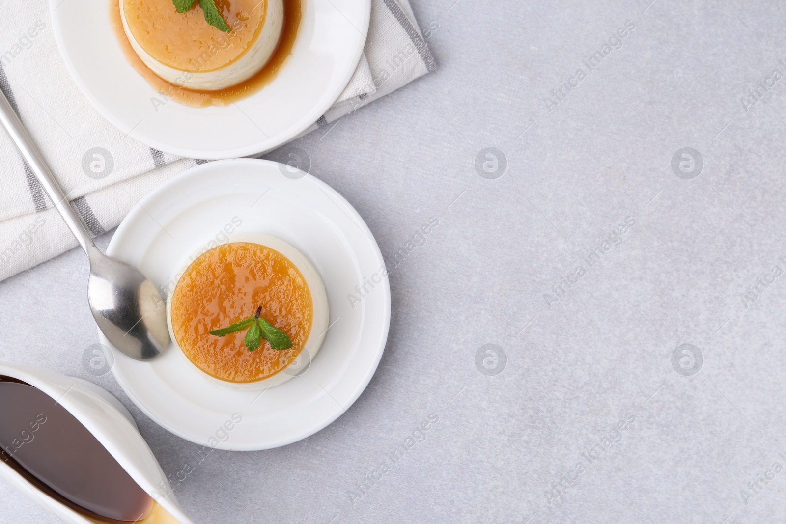 Photo of Tasty pudding with caramel sauce served on white table, flat lay. Space for text