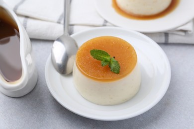 Photo of Tasty pudding with caramel sauce served on white table, closeup