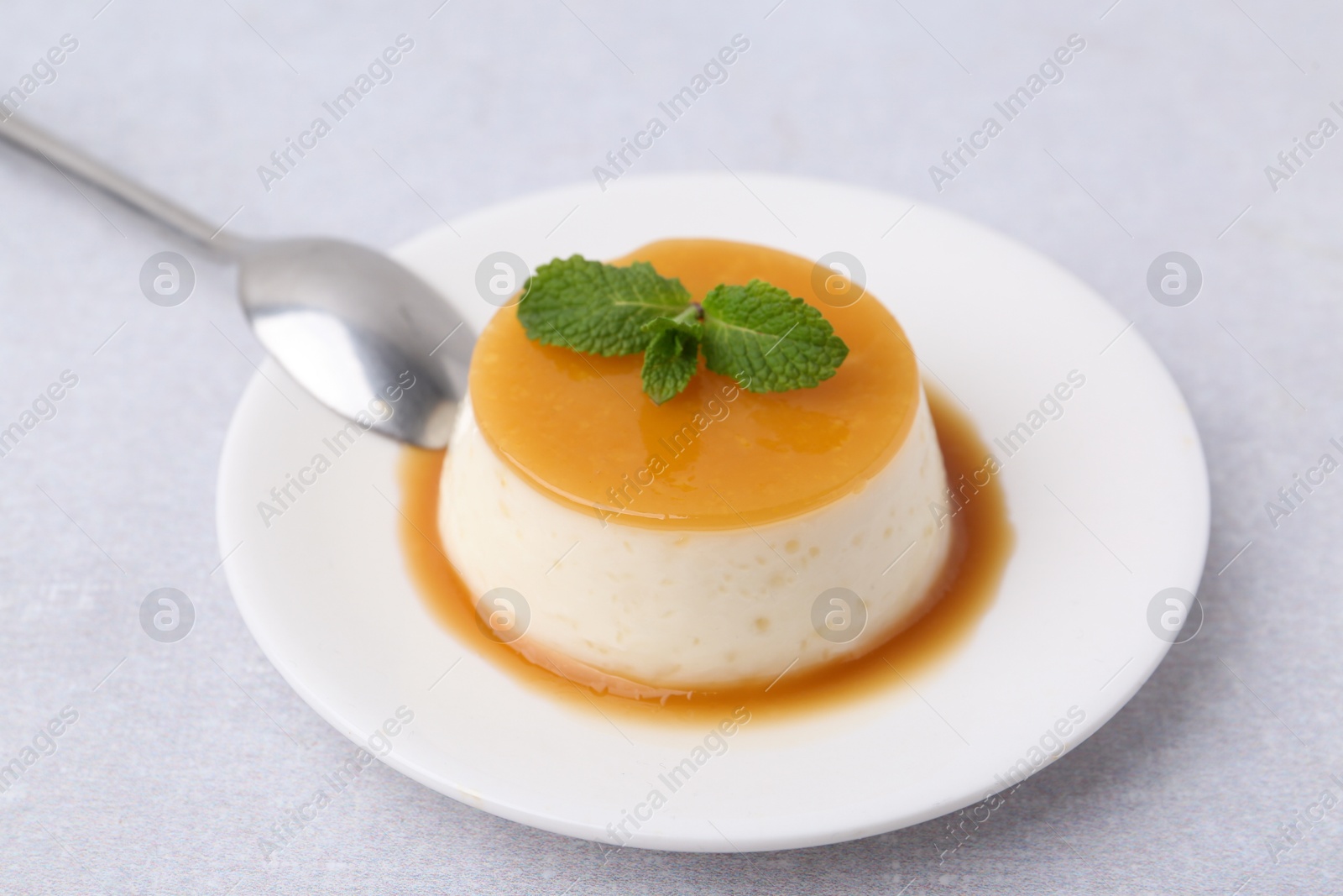 Photo of Tasty pudding with caramel sauce served on white table, closeup