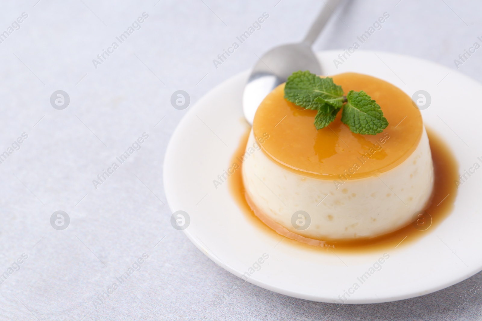 Photo of Tasty pudding with caramel sauce served on white table, closeup. Space for text