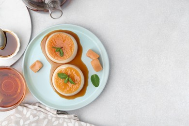 Photo of Tasty puddings with caramel sauce served on white table, flat lay. Space for text