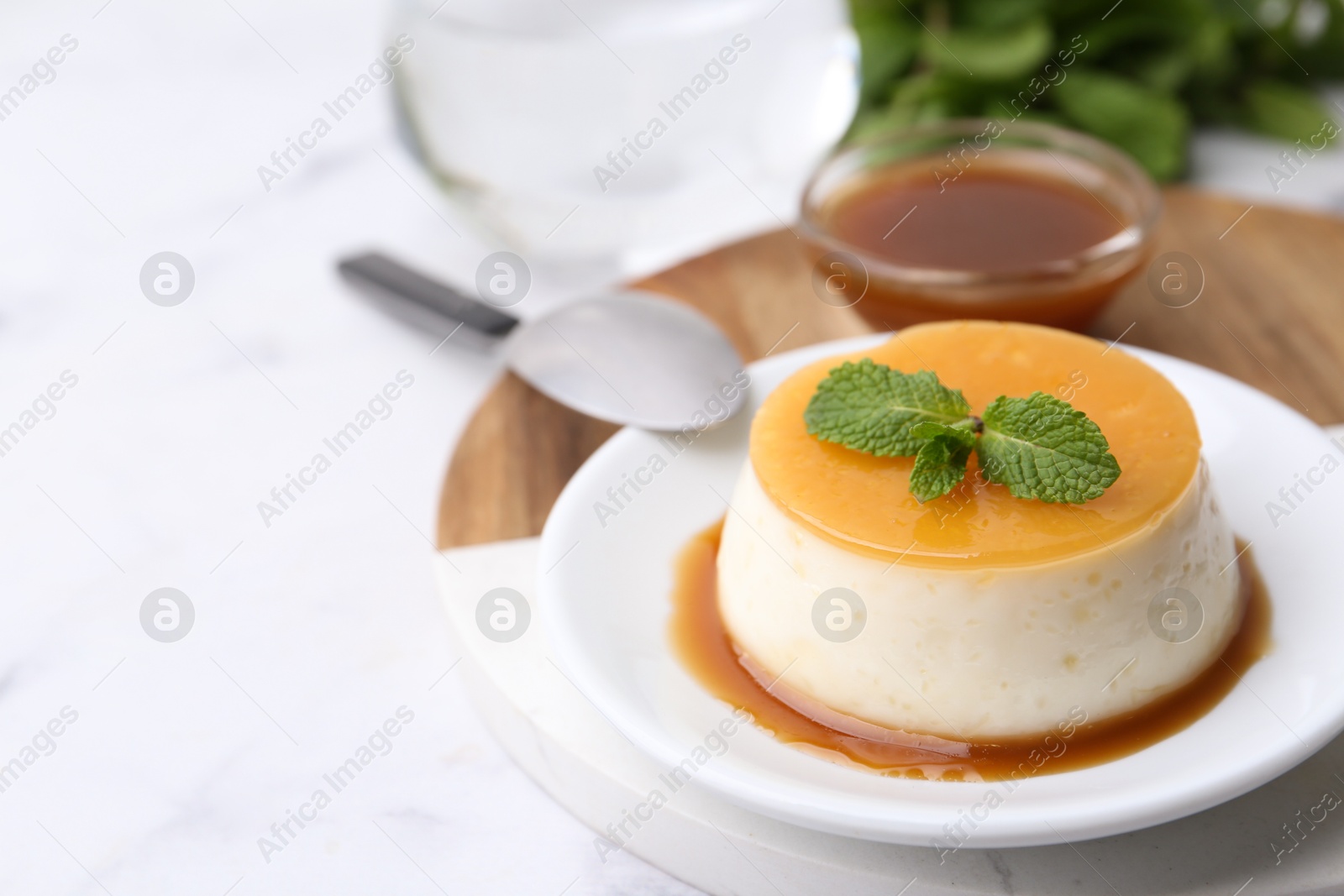 Photo of Tasty pudding with caramel sauce served on white marble table, closeup. Space for text