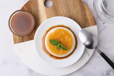 Photo of Tasty pudding with caramel sauce served on white marble table, top view