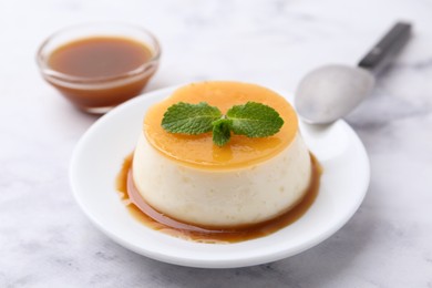 Photo of Tasty pudding with caramel sauce served on white marble table, closeup