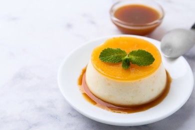 Photo of Tasty pudding with caramel sauce served on white marble table, closeup. Space for text